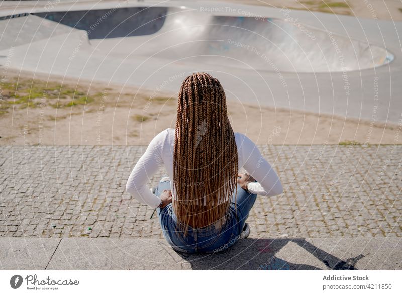 Stilvolle ethnische Frau in Rollschuhen im Skatepark Rollerblade Skateplatz cool Sommer Hobby trendy Rampe Geflecht schwarz Afroamerikaner Jeansstoff sorgenfrei