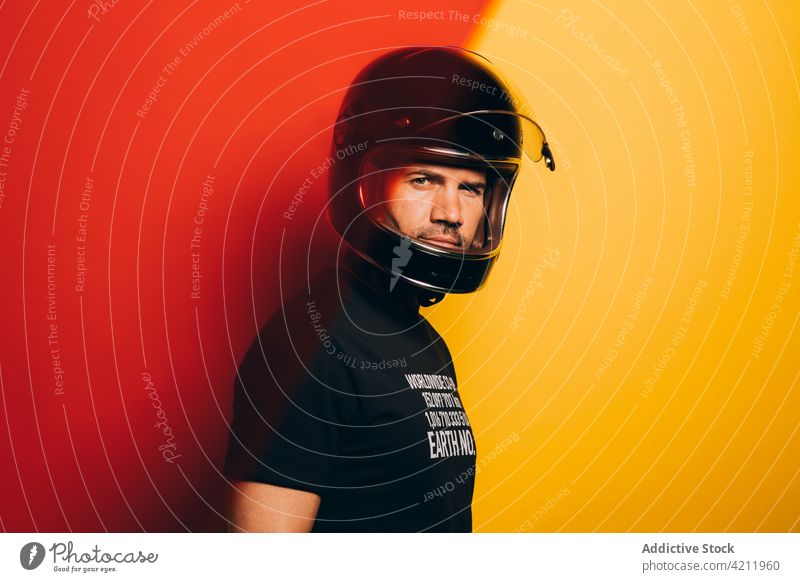 Seriöser männlicher Motorradfahrer mit Helm schaut in die Kamera Mann Schutzhelm Biker Rennfahrer selbstbewusst ernst behüten brutal schwarz Erwachsener Stil