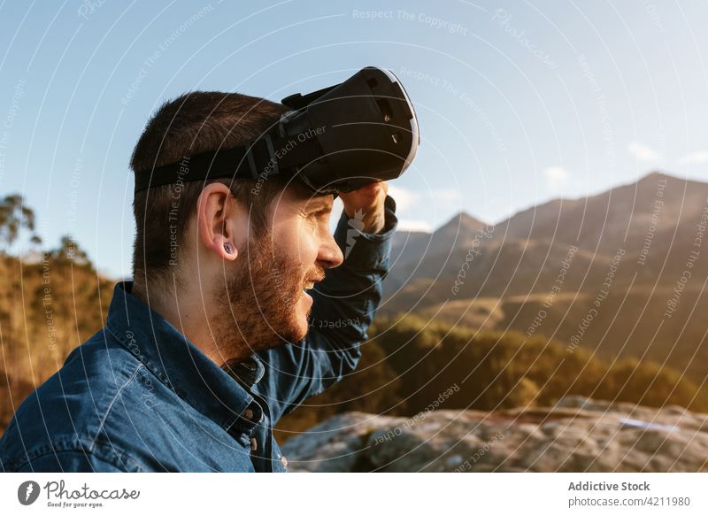 Reisender Mann mit VR-Brille in den Bergen virtuell Realität Berge u. Gebirge Erfahrung Hochland Schutzbrille reisen männlich Abenteuer genießen Hügel erkunden