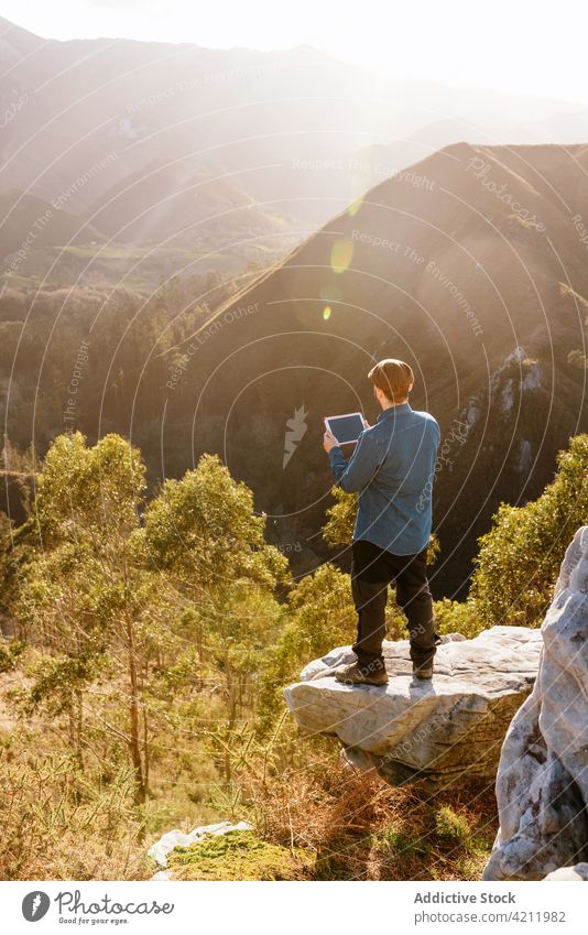 Reisender mit Tafel auf einem felsigen Hügel im Hochland Berge u. Gebirge Mann bewundern genießen Aussichtspunkt Tablette Freiheit stehen reisen männlich Urlaub