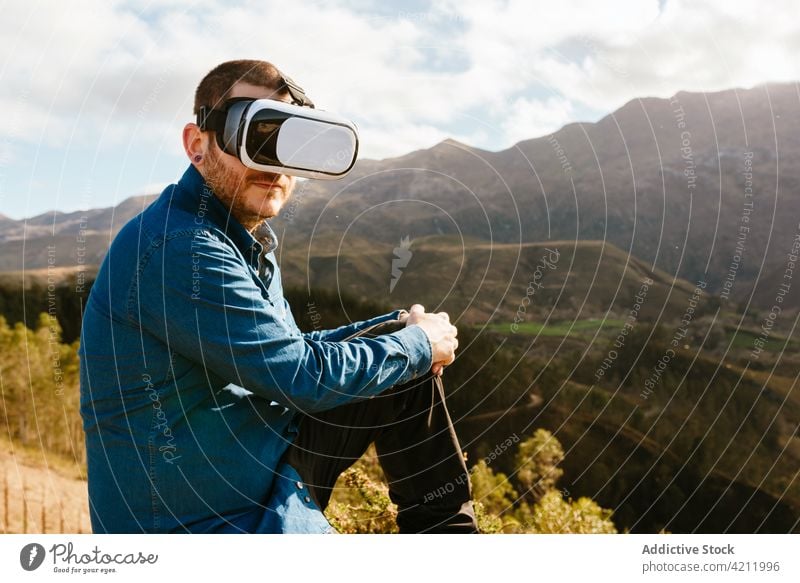 Reisender Mann mit VR-Brille in den Bergen virtuell Realität Berge u. Gebirge Erfahrung Hochland Schutzbrille reisen männlich Abenteuer genießen Hügel erkunden