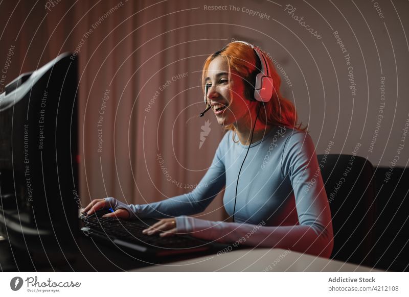 Fröhlicher Gamer beim Spielen eines Videospiels Spieler Frau spielen Kopfhörer Glück heimwärts Gerät Apparatur benutzend zuhören froh Internet positiv