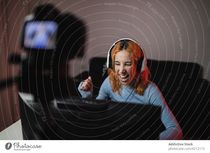 Fröhliche weibliche Gamerin, die ein Video für einen Blog aufnimmt Spieler Frau schießen Aufzeichnen soziale Netzwerke Blogger Lächeln Apparatur Audio