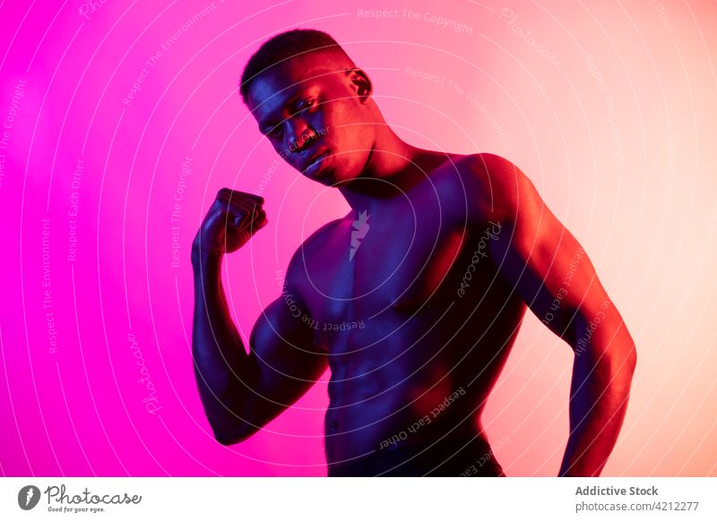 Ernster, hemdloser afroamerikanischer Mann mit Fäusten im Studio sportlich Stärke ernst muskulös Athlet selbstbewusst mit der Faust nach oben Studioaufnahme