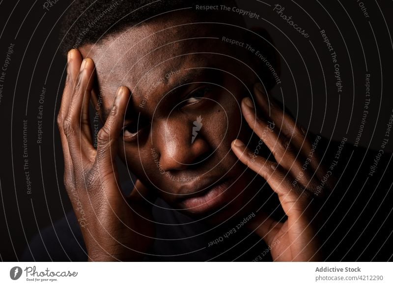 Müder afroamerikanischer Mann mit Händen auf dem Gesicht im Studio Migräne Porträt Kopfschmerzen Studioaufnahme ernst allein nachdenklich traurig müde