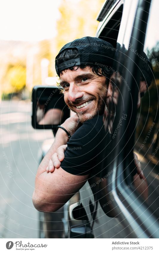 Glücklicher Geländewagenfahrer lehnt sich aus dem Fenster Mann Laufwerk Transport Porträt PKW im Freien fahren Lächeln Reise Emotion Fahrer Fröhlichkeit Blick