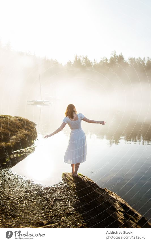 Frau auf einem Felsen stehend mit Blick auf einen See an einem nebligen Tag Nebel Natur Wasser Landschaft Menschen Mädchen im Freien Person schön Wald reisen