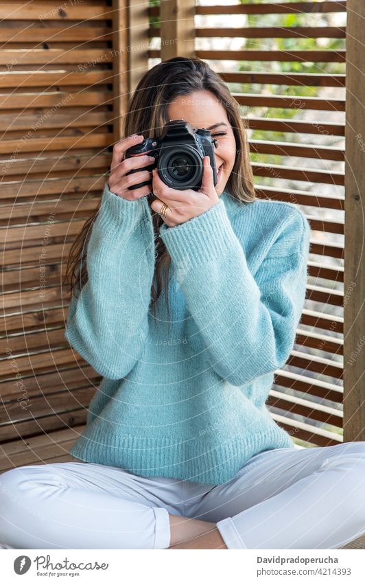 Junge Frau, die mit der Kamera von der Terrasse aus fotografiert Fotografie fotografieren Fotoapparat heiter Glück Hobby genießen Gerät Apparatur einfangen