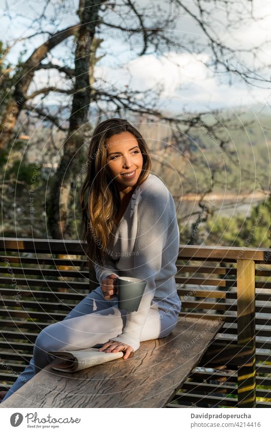 Lächelnde Frau entspannt auf Terrasse bei Sonnenuntergang Tasse trinken genießen Balkon Haus Natur heiter Sommer Kaffee Tee sich[Akk] entspannen Getränk
