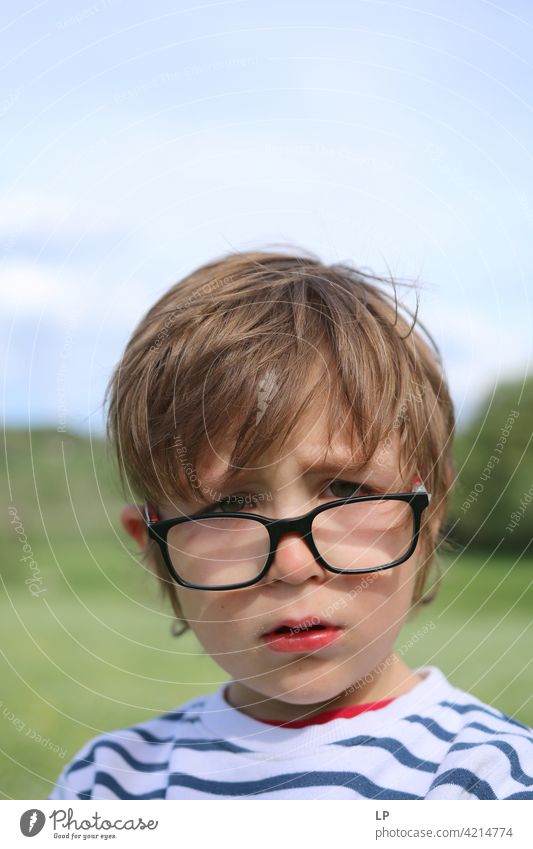 Kind, das eine Brille trägt, weint und in die Kamera schaut zögernd verwirrt ratlos skeptisch Zweifel zweifelhaft hestitate Unsicherheit Verwirrung Kindheit