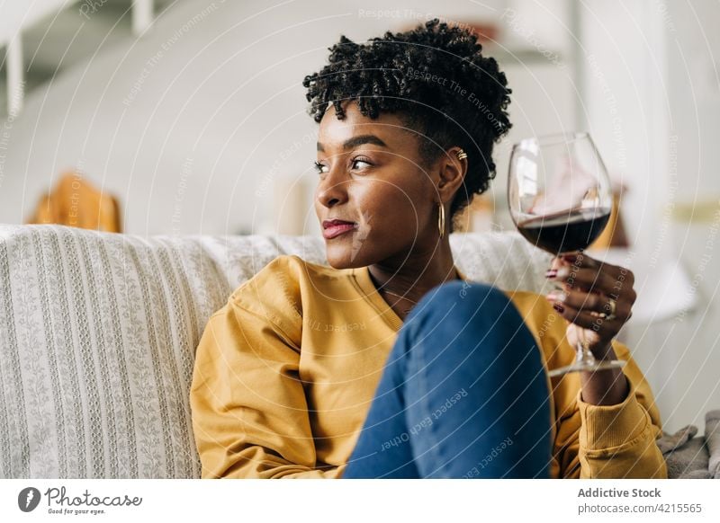 Schwarze Frau mit einem Glas Wein zu Hause heimwärts Weinglas Kälte Rotwein genießen trinken Wochenende schwarz ethnisch Afroamerikaner Getränk Glück sitzen