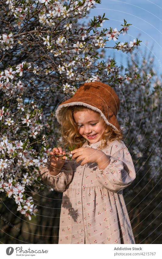 Niedliches kleines Mädchen im blühenden Garten im Frühling Blume Baum Blütezeit Porträt heiter geblümt Kleid Park Kind niedlich Lächeln wenig Glück Kindheit
