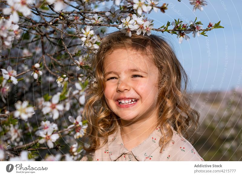 Niedliches kleines Mädchen im blühenden Garten im Frühling Blume Baum Blütezeit Porträt heiter geblümt Kleid Park Kind niedlich Lächeln wenig Glück Kindheit