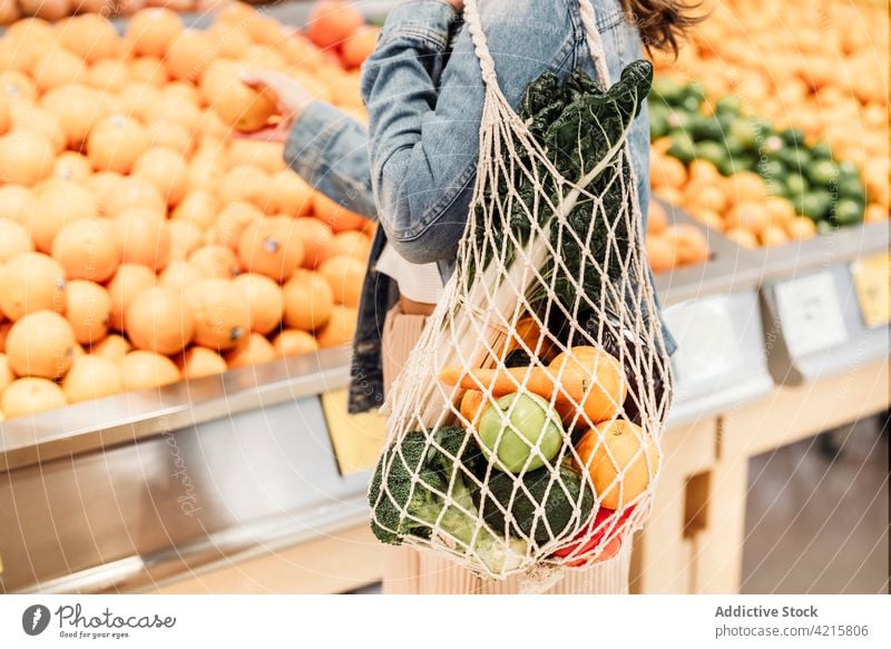 Crop-Frau mit frischen Lebensmitteln im Netzbeutel im Supermarkt ineinander greifen Tasche umweltfreundlich Lebensmittelgeschäft Käufer keine Verschwendung