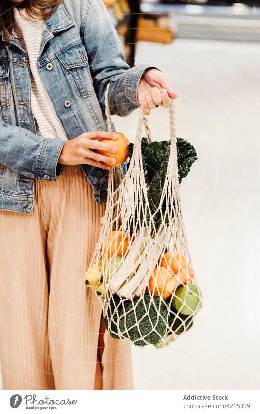 Anonyme Frau mit Netzbeutel voller reifer Lebensmittel Lebensmittelgeschäft ineinander greifen Tasche Baumwolle umweltfreundlich keine Verschwendung Frucht