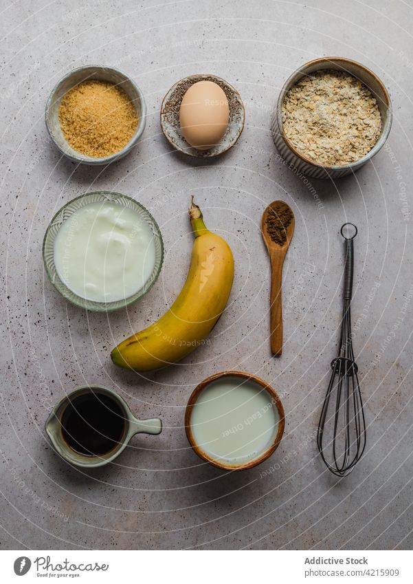 Zusammensetzung der Zutaten für die Zubereitung von Bananenpfannkuchen Ei Sahne Zucker Zimt Hintergrund Sirup Vanille Pfannkuchen Löffel Draufsicht von oben