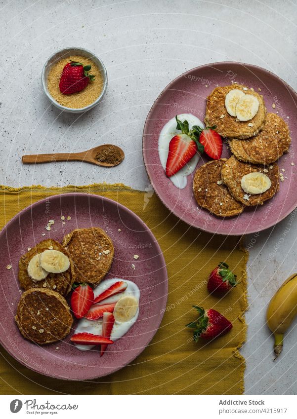 Mit Bananenpfannkuchen und ein paar Erdbeerstücken belegen Dessert süß Frühstück Lebensmittel Erdbeeren Zucker Sahne selbstgemacht Amerikaner lecker Pfannkuchen
