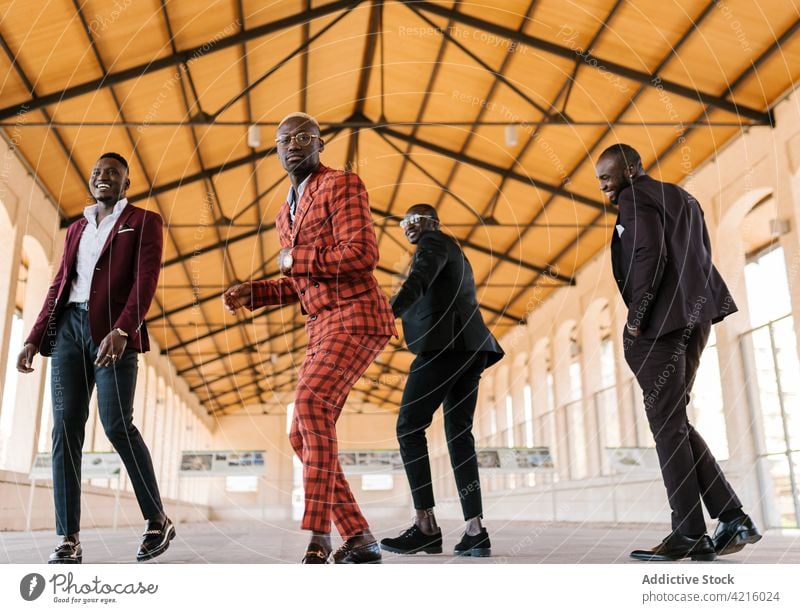 Schwarze Männer in schicken Anzügen haben Spaß im Gebäude Tanzen Spaß haben Stil Mode genießen Individualität cool aktiv maskulin Brille Afro-Look Geflecht