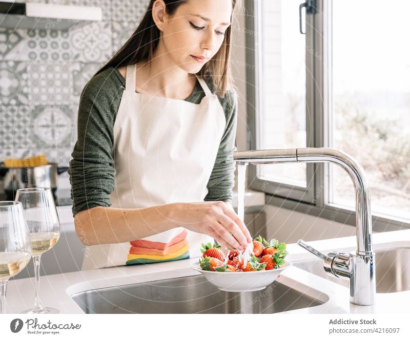 Eine Frau wäscht zu Hause Erdbeeren unter fließendem Wasser Waschen Wasserhahn Vitamin lecker natürlich Küche Porträt eingießen gesunde Ernährung Prozess