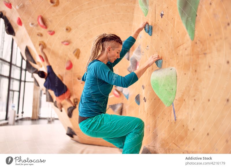 Konzentrierte Sportlerinnen und Sportler beim Training im Kletterzentrum Aufstieg Wand Felsbrocken stark Aufsteiger Griff Übung Gleichgewicht extrem Bergsteiger