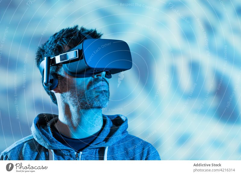 Anonymer Mann erlebt virtuelle Realität in einer Schutzbrille Headset VR erkunden eintauchen simulieren Technik & Technologie Entertainment neonfarbig benutzend