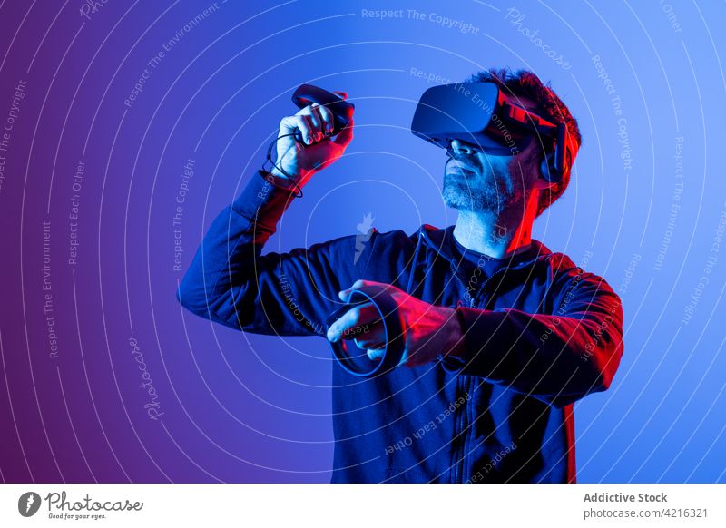 Unbekannter Mann in VR-Headset mit Controllern beim Spiel Virtuelle Realität spielen Regler eintauchen Technik & Technologie unterhalten benutzend Apparatur