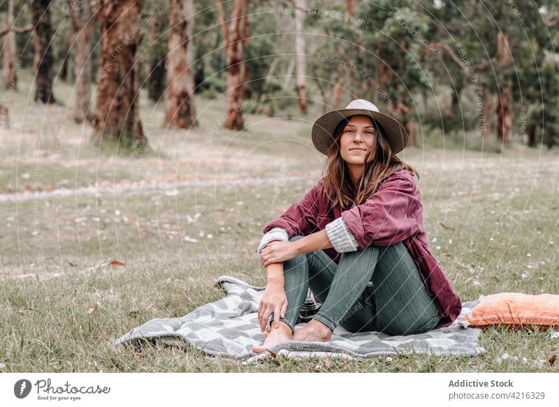 Zufriedene Frau beim Picknick auf einer Decke im Wald sitzend Inhalt genießen Wiese sorgenfrei Plaid Sommer Australien Glück Lächeln ruhen Natur Freude Umwelt