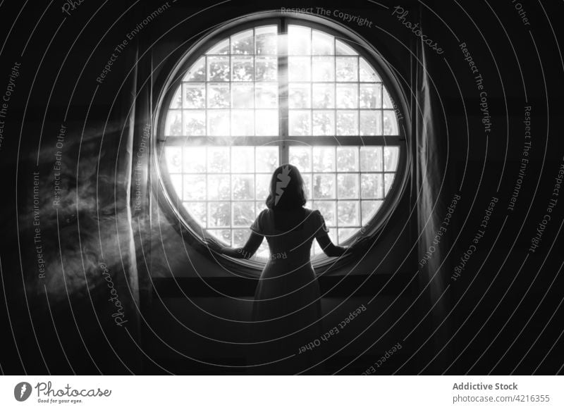 Anonyme Frau schaut bei Sonnenschein zu Hause aus dem Fenster herausschauen Einsamkeit sanft Zauberei u. Magie Angebot feminin romantisch idyllisch heimwärts