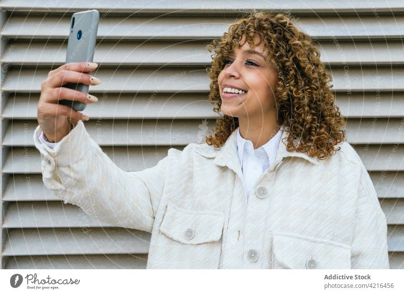 Lächelnde schwarze Frau macht Selfie in der Stadt Selbstportrait Smartphone heiter Afro-Look Frisur Großstadt Gedächtnis Moment ethnisch Afroamerikaner urban
