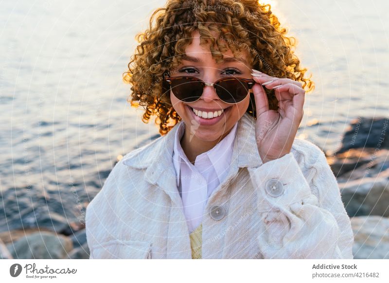 Schwarze Frau genießt die Freiheit am Meer genießen Meeresufer Sonnenuntergang Arme heiter Seeküste ethnisch schwarz Afroamerikaner Sonnenbrille Sommer Feiertag