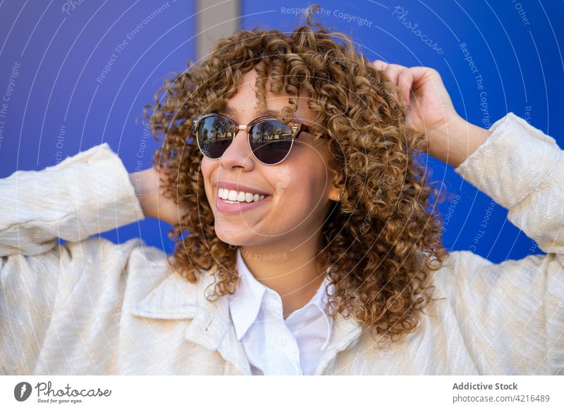 Fröhliche schwarze Frau mit lockigem Haar heiter sorgenfrei Freude krause Haare Afro-Look Frisur Atelier Glück ethnisch Afroamerikaner charmant Sonnenbrille