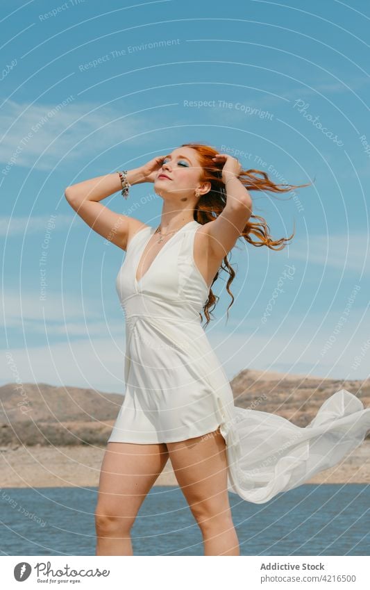 Feminine Frau mit fliegendem Haar am See im Sommer fliegendes Haar Augen geschlossen feminin verträumt romantisch sanft Verlockung Porträt wolkig Blauer Himmel