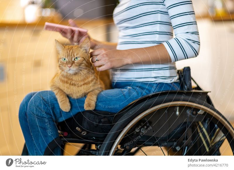 Frau im Rollstuhl mit Katze auf dem Schoß häusliches Leben Behinderung deaktiviert Selbstvertrauen unabhängig im Innenbereich heimwärts Haus Menschen jung