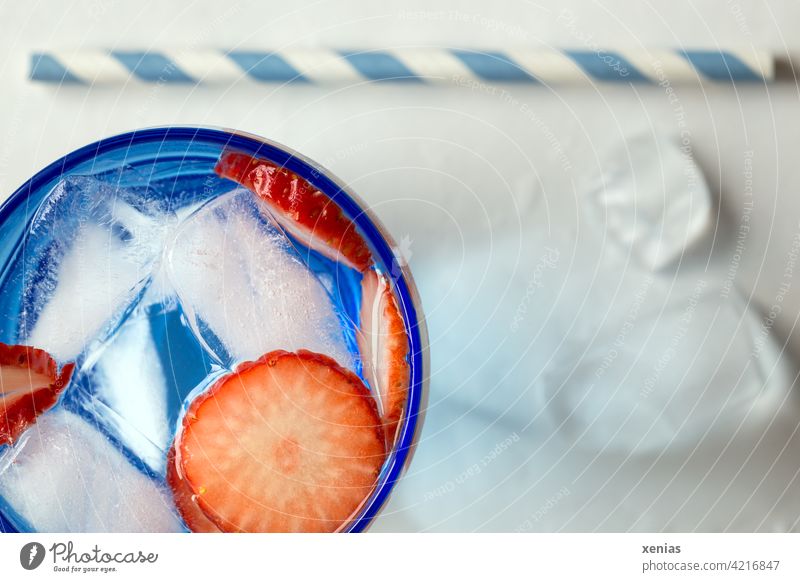Aromatisches frisches Wasser mit Erdbeere und Eiswürfel, Trinkhalm liegt bereit Getränk Erfrischungsgetränk Obst Frucht kalt erfrischend Detox blau rot weiß