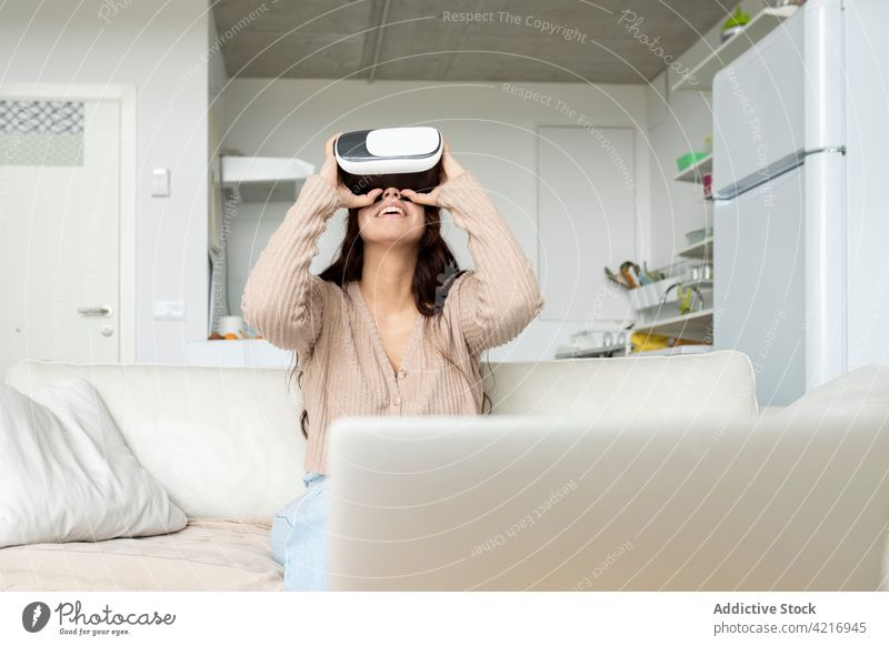 Unkenntlich lächelnde Frau, die zu Hause mit einer Brille virtuelle Realität erlebt Schutzbrille Virtuelle Realität Erfahrung Entertainment
