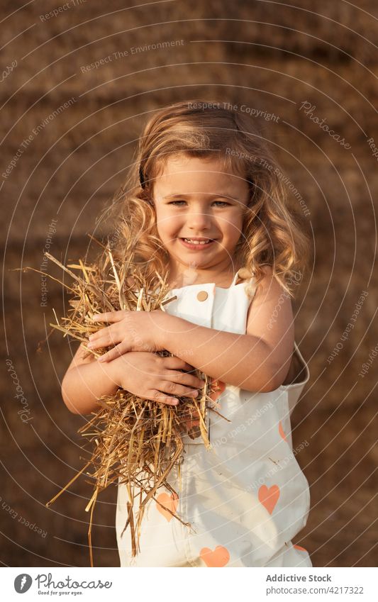 Niedliches Mädchen spielt mit Stroh im Feld Ballen Heu spielen Spaß haben Landschaft heiter Kind Kindheit niedlich bezaubernd Natur gesamt idyllisch wenig Glück