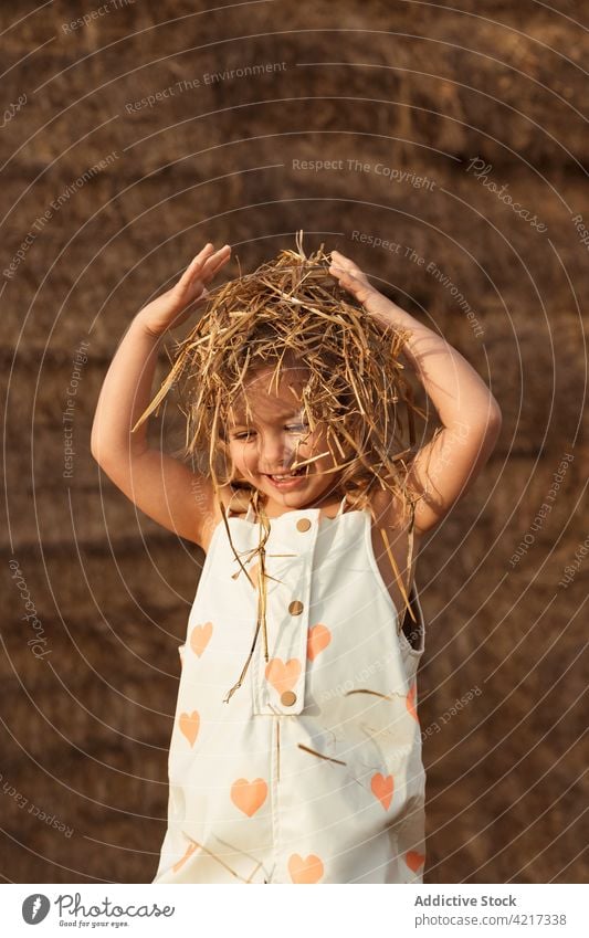 Niedliches Mädchen spielt mit Stroh im Feld Ballen Heu spielen Spaß haben Landschaft heiter Kind Kindheit niedlich bezaubernd Natur gesamt idyllisch wenig Glück