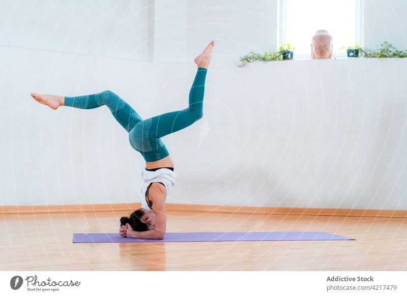 Unerkennbare Frau, die einen gestützten Kopfstand mit Spagat im Zimmer ausführt angehobene Beine Gleichgewicht Yoga Umkehrung Talent Fähigkeit üben Haus perfekt