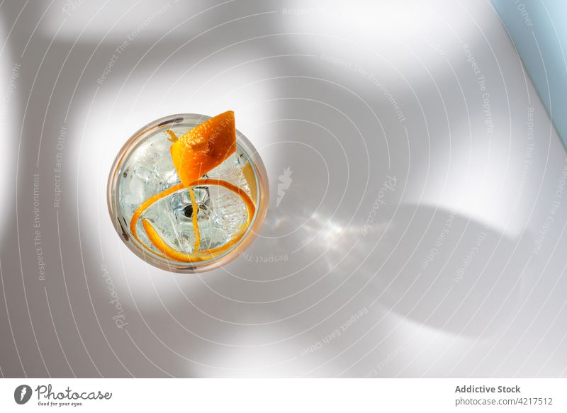 Glas Gin Tonic mit Orangenzesten auf dem Tisch Cocktail Alkohol hochball orange Schale Gewürznelke Schatten Wittern hell kreativ Design Wasser Aroma