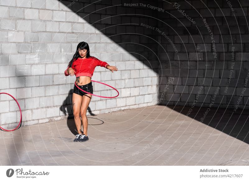 Tänzerin dreht Hula-Hoop-Reifen auf dem Bürgersteig spinnen Tanzen aktiv passen Tattoo Frau herumwirbeln Bewegung Choreographie Schatten Körper selbstbewusst