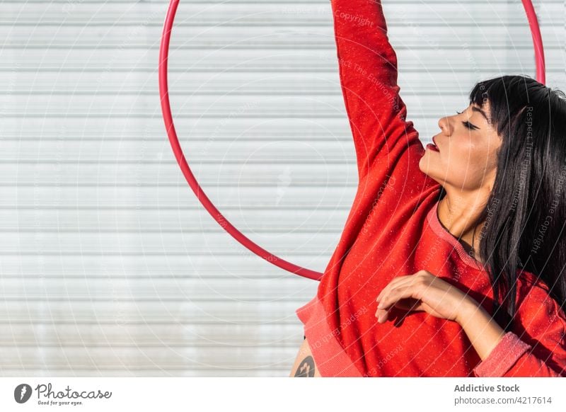Tänzerin dreht Hula-Hoop-Reifen mit erhobenem Arm auf dem Bürgersteig spinnen Tanzen Arm angehoben aktiv passen Tattoo Frau herumwirbeln Bewegung Choreographie