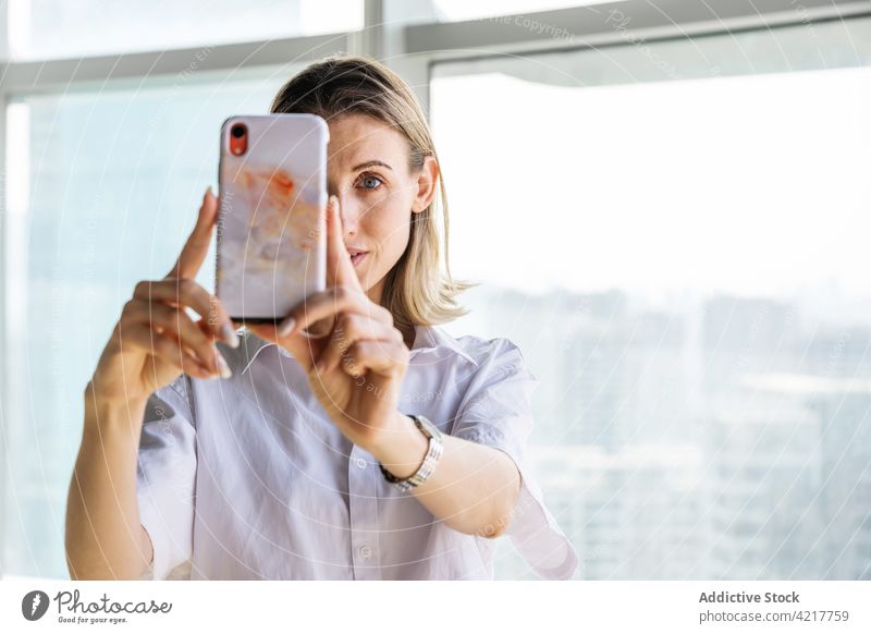 Frau macht Selfie im Büro mit Smartphone blond Porträt Foto Mobile lässig Telefon Kaukasier Großstadt Stadtbild Selbstportrait Gedächtnis Textfreiraum Gerät