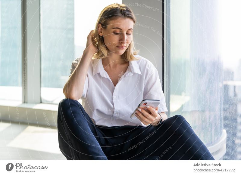 Frau in leerem Büro, die ein Smartphone benutzt schwarze Hose blond hell Gebäude nachdenklich Kaukasier Handy Textfreiraum Gerät Mobile Telefon Browsen jung