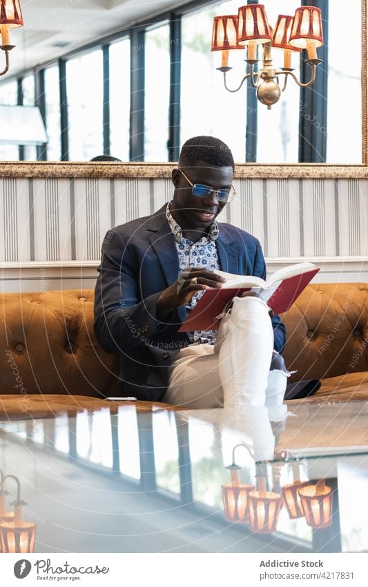 Nachdenklicher schwarzer Geschäftsmann, der in einem Café ein Buch liest lesen Unternehmer elegant gut gekleidet Literatur besinnlich Fokus männlich ethnisch