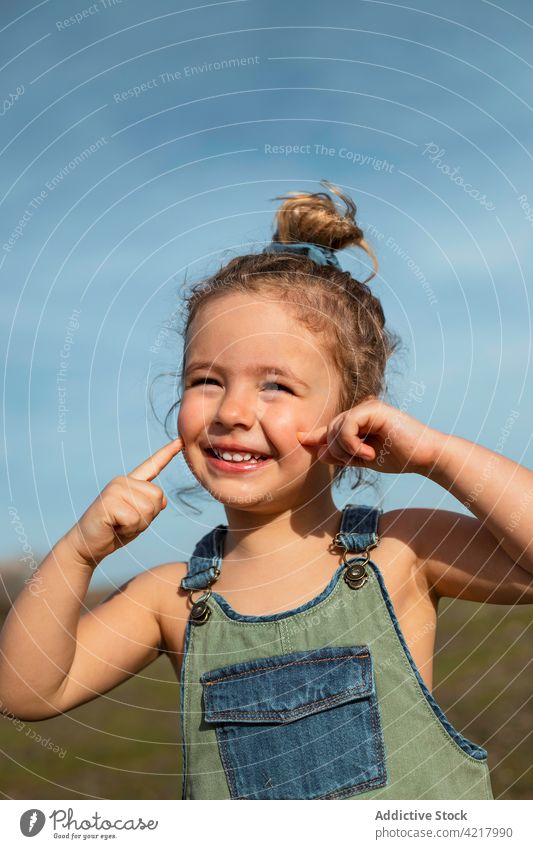 Lächelndes kleines Mädchen auf einem Feld im Sommer gesamt Stil niedlich wenig Outfit heiter sonnig Glück Kindheit Optimist Freude Wiese sorgenfrei froh stehen