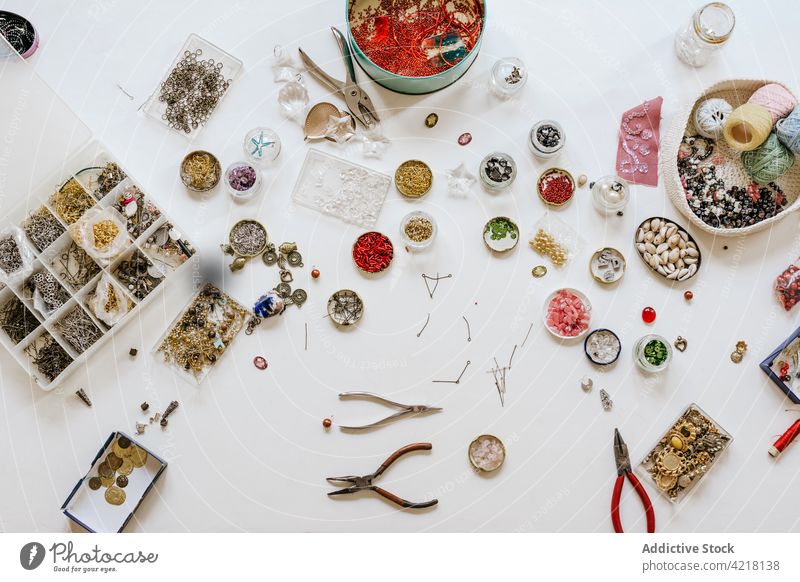 Tisch mit verschiedenen Dekorationen und Perlen zur Herstellung von Bijouterie Wulst Faser Accessoire Pailletten Zange Sammlung spangle dekorativ sortiert