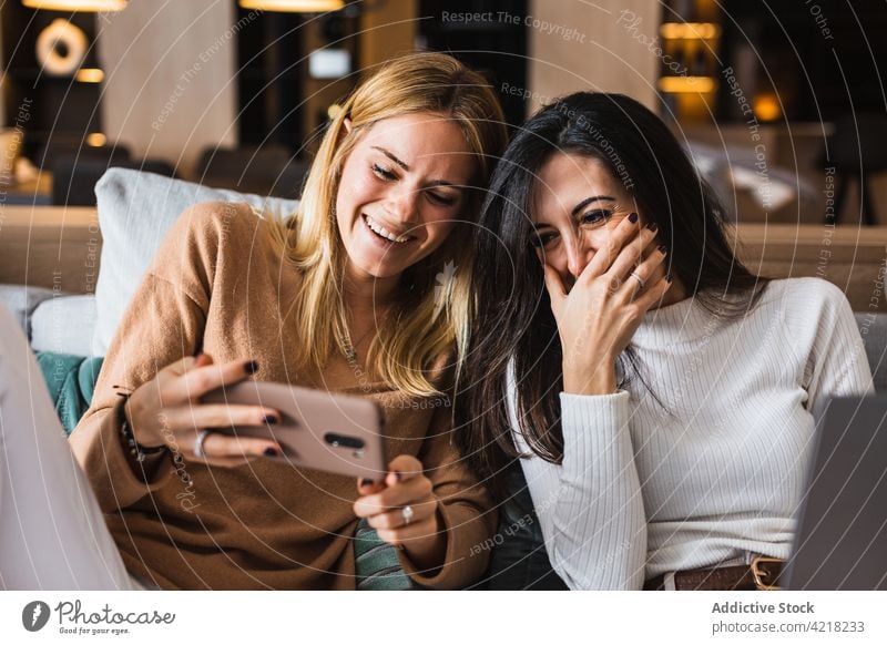 Fröhliche lesbische Frauen sehen sich ein lustiges Video auf einem Smartphone an Paar Lachen Spaß haben unterhalten zuschauen benutzend Telefon Apparatur heiter