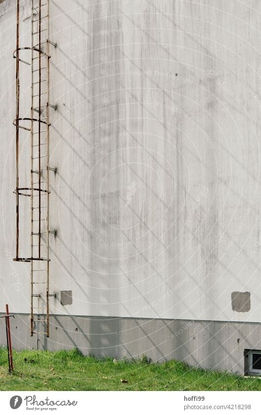 Schattenwurf einer Aussenleiter auf grauer Wand rostig fluchtleiter Leiter Fluchtweg Lagerhalle Hafen Fassade Industrie Industriefotografie Lagerhaus