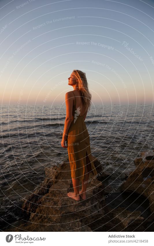 Friedliche Frau am Abend an der Felsenküste stehend Ufer MEER Natur Umwelt Sonnenuntergang Feiertag sorgenfrei Harmonie friedlich Urlaub winken Meeresufer