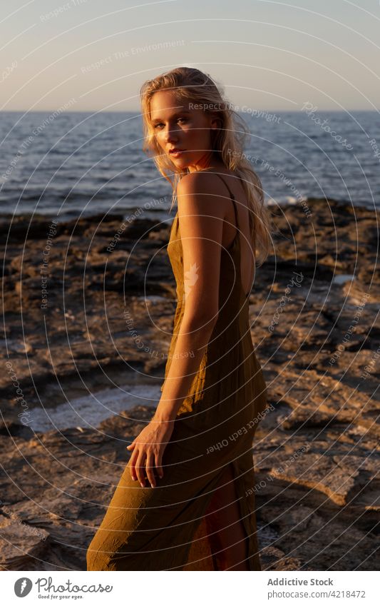 Friedliche Frau am Abend an der Felsenküste stehend Ufer MEER Natur Umwelt Sonnenuntergang Feiertag sorgenfrei Harmonie friedlich Urlaub winken Meeresufer